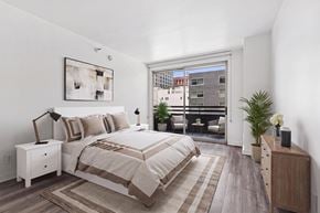 Los Angeles apartment for rent - A bedroom with a large bed and a view of a cityscape through a window.